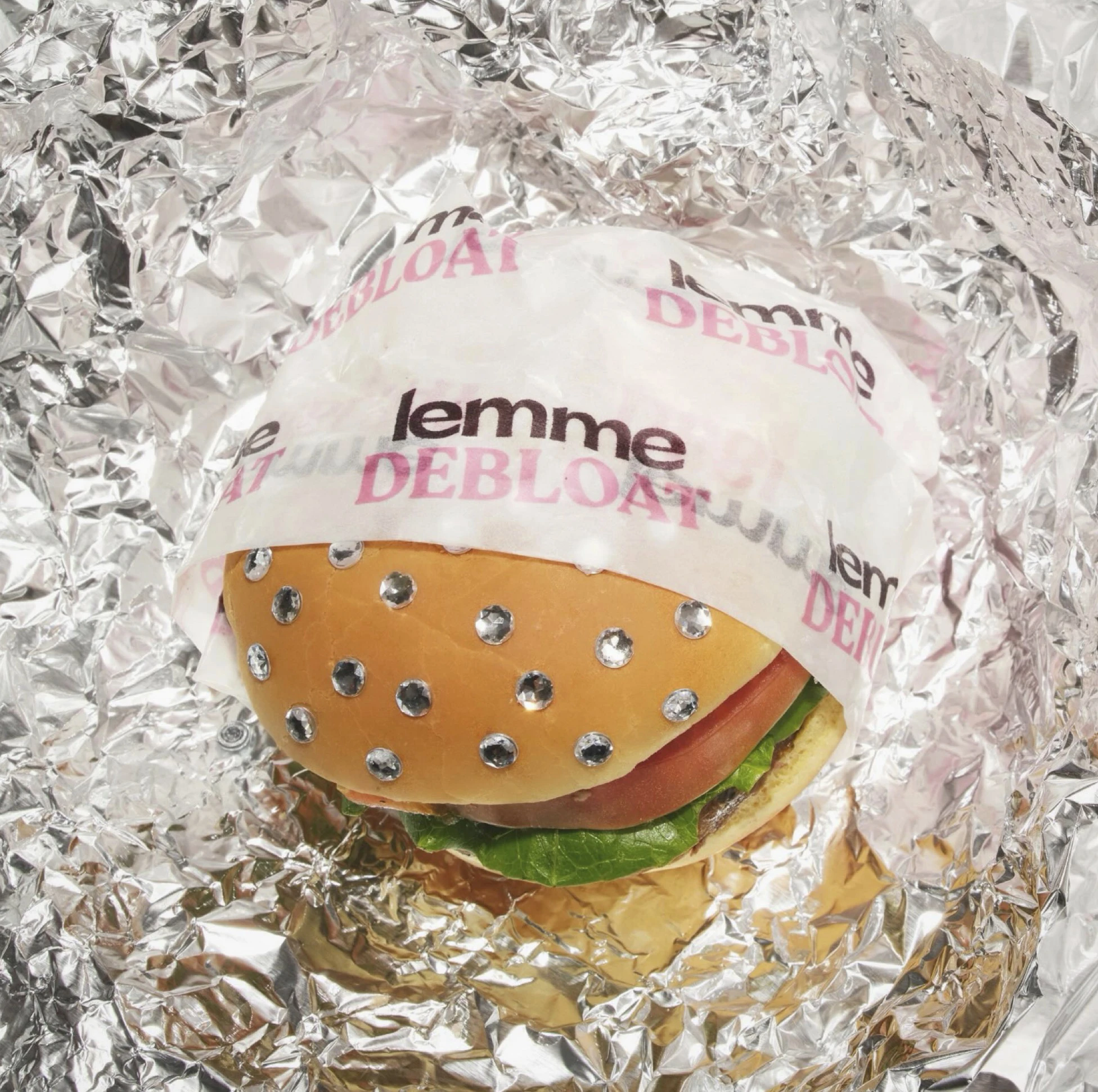 a burger wrapper printed on thin glossy paper wrapped around a bedazzled hamburger